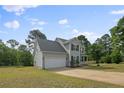 A side view captures a charming home with a two-car garage, a well-maintained lawn, and mature trees at 140 Chinkapin Oak Cir, Bunnlevel, NC 28323