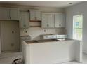 New kitchen with white cabinets, an island, and a large window for natural light at 171 Travelers Way, Lillington, NC 27546