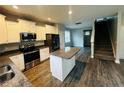Modern kitchen boasts stainless steel appliances, white cabinets, an island, and sleek gray wood floors at 4179 Overhills Rd, Spring Lake, NC 28390