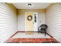 Inviting front porch with a bright yellow door and a cozy wicker chair at 2068 Tingen Rd, Broadway, NC 27505