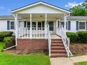 View of the home's cozy front porch with brick foundation, white railing, and steps leading to the front door at 99 Allen Brown Ln, Erwin, NC 28339