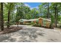 Charming single-story brick home featuring a sprawling front yard and attached two-car garage nestled among mature trees at 3113 Chipping Wedge, Sanford, NC 27330