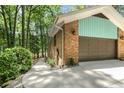 Side view of brick home showcasing a garage, landscaped walkway, and verdant greenery at 3113 Chipping Wedge, Sanford, NC 27330