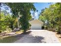 View of the home's facade, showcasing the driveway and mature trees surrounding the property on a sunny day at 70 Oregon Ln, Spring Lake, NC 28390
