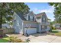 View of the side of a charming two-story home with gray siding and an attached garage at 717 Lenoir Dr, Spring Lake, NC 28390