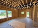 Partially framed living room with large windows, door to the outside, and exposed ceiling at 235 Atkins Rd, Cameron, NC 28326
