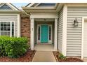 Inviting front entrance with a vibrant teal door and well-maintained landscaping at 49 Infantry Dr, Cameron, NC 28326