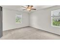 Spacious bedroom with neutral carpet, a ceiling fan, two windows and freshly painted white walls at 641 Avery Pond Dr, Fuquay Varina, NC 27526