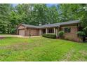 Ranch-style home with brick facade, attached garage, manicured lawn, and lush green surroundings at 2024 Sandalwood Dr, Sanford, NC 27332