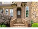 A detailed view of the front entrance with brick steps, an arched doorway, and decorative landscaping at 4012 Sorrell Brothers Ct, Raleigh, NC