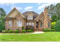 Charming brick home with stone chimney, manicured lawn, and beautiful landscaping at 4012 Sorrell Brothers Ct, Raleigh, NC