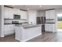 Modern kitchen with white cabinets, stainless steel appliances, granite countertops and gray wood flooring at 107 Camp Rock Rd, Lillington, NC 27546