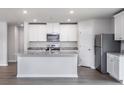 Modern kitchen with white cabinets, stainless steel appliances, granite countertops and gray wood flooring at 107 Camp Rock Rd, Lillington, NC 27546