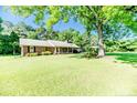 Spacious front yard with mature shade trees enveloping a charming brick home featuring a metal roof at 3897 Olivia Rd, Sanford, NC 27332
