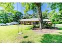 Tree swing with a charming brick home in the background nestled within a spacious lot and mature shade trees at 3897 Olivia Rd, Sanford, NC 27332