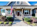 Charming front porch with stone pillars, complemented by manicured landscaping and an American flag at 30 Regal Pond Dr, Angier, NC 27501