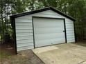Metal detached garage with a roll-up door and concrete pad for convenience at 467 Deep River Rd, Sanford, NC 27330