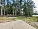 Spacious backyard with a metal fence, mature trees, access to a lake, and a concrete patio at 147 Sherwood Ln, Sanford, NC 27332