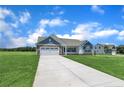 A single-story home featuring a two-car garage on a lush green lawn with blue sky and clouds overhead at 127 Camp Rock Rd, Lillington, NC 27546