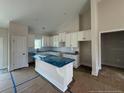 Bright kitchen with white cabinets, island with blue cover, and modern appliances, ready for finishing touches at 127 Camp Rock Rd, Lillington, NC 27546