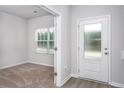 Entryway featuring carpet in an adjacent room, a white door, and luxury vinyl plank flooring at 158 Camp Rock Rd, Lillington, NC 27546