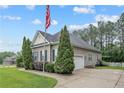 Home exterior featuring an attached garage, driveway, lush lawn, well maintained landscaping, and American flag at 45 Remington Hills Dr, Bunnlevel, NC 28323