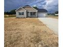 An inviting single-story home with a manicured lawn and a paved driveway leading to an attached garage at 24 Roll Tide Ct, Angier, NC 27501