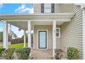 Front porch with white columns, a light blue front door, manicured bushes, and a well kept lawn at 94 Heatherwood Dr, Lillington, NC 27546