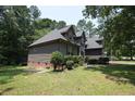 Landscaped yard surrounding a two-story home with brick foundation and muted brown siding at 98 Pineridge Cv, Sanford, NC 27332