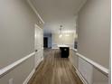 Hallway leading to open kitchen with hardwood floors and white wainscoting at 220 Gallery Dr # 201, Spring Lake, NC 28390