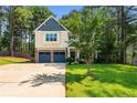Charming two-story home with blue garage doors, manicured lawn, and mature trees at 55 High Green Pt, Cameron, NC 28326