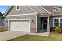 Detailed view of the home's entrance, two-car garage, and well-maintained landscaping at 139 Ravens Row Dr, Benson, NC 27504