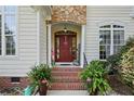 Stylish covered front entry featuring a red front door, brick steps, and decorative plants at 256 Barons W Run, Spring Lake, NC 28390