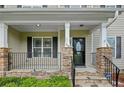 Inviting front porch with stone pillars, a black railing, and stylish front door at 116 Springside Dr, Spring Lake, NC 28390