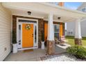 Cozy front porch with decorative columns, a bright orange door, and manicured landscaping at 152 Century Dr, Cameron, NC 28326
