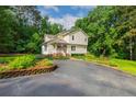 Two-story home with yellow siding, front porch, paved drive, and mature landscaping at 1718 Carthage St, Sanford, NC 27330