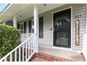 Cozy front porch featuring a welcome sign, a black screen door, and freshly painted white railings at 225 Woodshire Dr, Lillington, NC 27546