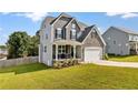 Well-manicured lawn complements a two-story home with stone accents and a two-car garage at 334 Bunting Dr, Lillington, NC 27546
