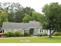 Charming single-story home with gray siding, white trim, landscaped yard, and a welcoming front porch adorned with an American flag at 4903 Lemon Springs Rd, Sanford, NC 27332
