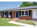 Close up of the brick front of a well-maintained single-story home with blue front door at 108 Pine St, Dunn, NC 28334