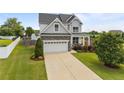 View of home showcasing the driveway, lawn, mature trees, and architectural details at 81 Dot Ct, Fuquay Varina, NC 27526