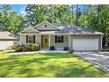 Charming single-story home with gray siding, black shutters, a welcoming yellow front door, and an attached two-car garage at 1541 Louisiana, Sanford, NC 27332