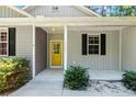 Inviting front entryway features a bright yellow door, black shutters, and well-maintained landscaping at 1541 Louisiana, Sanford, NC 27332