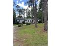 Ranch-style home with gray siding and an unpaved driveway surrounded by grass and tall trees at 47 Hunter Field, Sanford, NC 27332