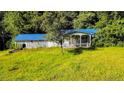 Charming home featuring a blue metal roof, complemented by a cozy porch and lush greenery at 2708 Nc 87 S Hwy, Cameron, NC 28326