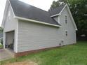 Exterior side view of home featuring attached garage and partial brick foundation at 2734 Sunnybrook Dr, Sanford, NC 27330