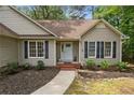 Inviting front entrance with a white door, black shutters, and landscaped garden beds at 40 Blue Heron Ct, Sanford, NC 27332
