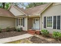 Inviting front entrance with a white door, black shutters, and landscaped garden beds at 40 Blue Heron Ct, Sanford, NC 27332