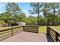 A wooden deck with horizontal railings overlooks a well-maintained lawn and lush trees at 428 Basket Oak Dr, Bunnlevel, NC 28323
