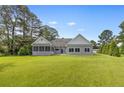 View of the back of the house features a large yard, screened porch, and a wall of windows at 56 Indian Trl, Sanford, NC 27332